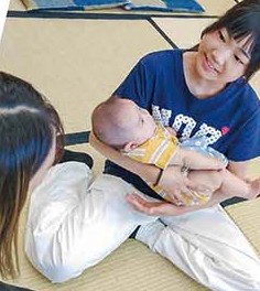 赤ちゃんを抱っこする中高生